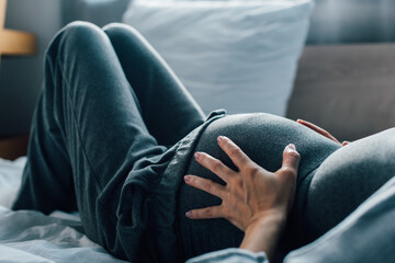 cropped view of pregnant woman suffering from pain in bedroom