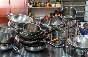 A lot of metal pots and pans on the kitchen table.
