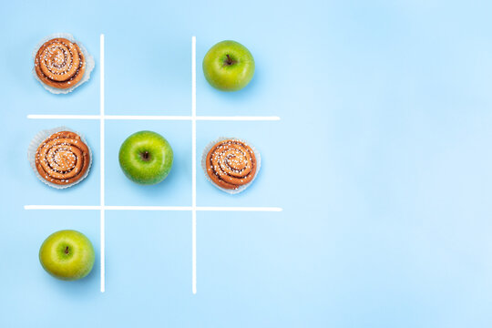 Healthy Vs Unhealthy Food, Green Apples Vs Cinnamon Buns In Tic Tac Toe Or Noughts And Crosses Game, Horizontal, Top View, Copy Space