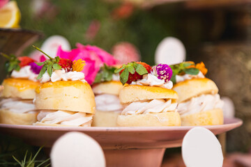 Scones and cream with pretty flowers decorating them.