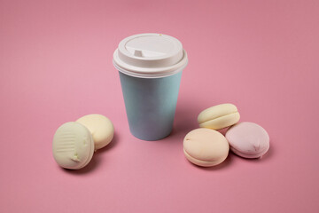 Paper cup with coffee and macaroons on a pink background