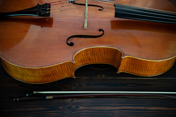 The cello lies on a wooden surface. Place for text