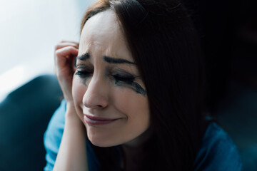 Fototapeta premium depressed woman with flowed mascara crying at home