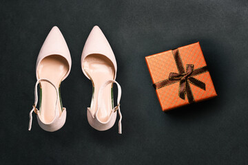 Shoes and a gift box on a black background. Fashionable and stylish women's shoes. Minimal style on a dark background.