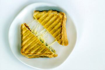 A grilled sandwich of melting cheese, on a white plate. 
