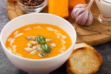Pumpkin cream soup with seeds on a stone background