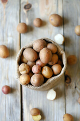 Selective focus. Small raw potatoes in a bag. Baby potatoes. Rustic style. Rustic potatoes.
