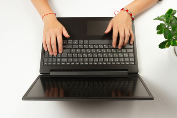 Fototapeta na wymiar female hands are typing text on laptop keyboard on white wooden table background