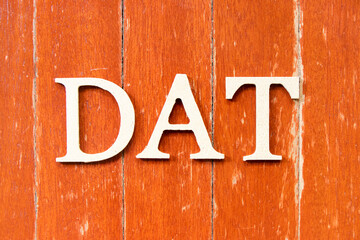 Alphabet letter in word DAT (Abbreviation of Delivery at Terminal) on old red color wood plate background