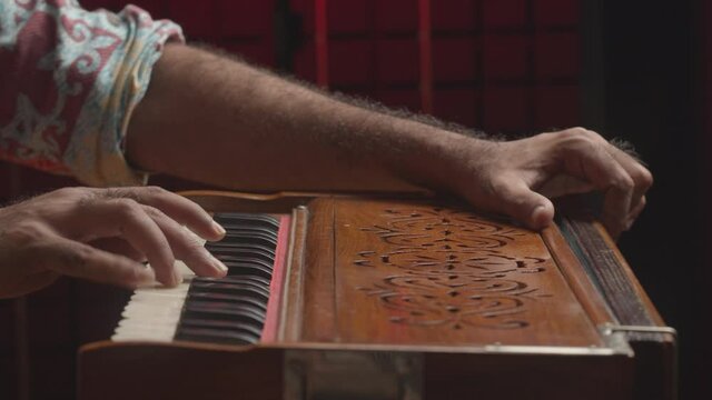 Music production studio. Creative world. Close up of an Indian man playing traditional instrument in the sound studio. Male person plays meditation music.