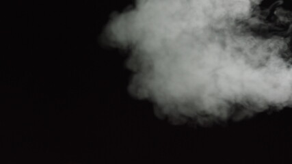 White water vapour on a black background. Close-up shot. White Fume Slowly Floating Rises Up. Abstract Haze Cloud. Animation Mist Effect. Smoke Stream Effect 4K