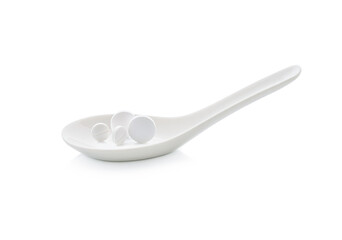 pills in the spoon and white tablets in the spoon.