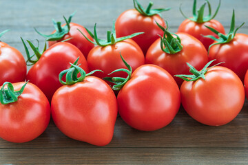 Fresh tomatoes lie on a wooden background.