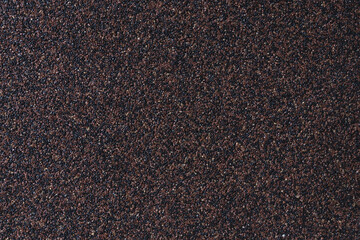 Dark wall made of varnished granite chips. Abstract construction surface. Rough industrial background. Seamless brown texture with copy space for text.