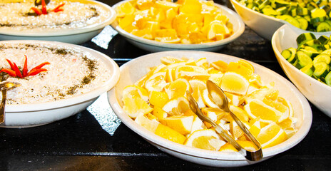 Catering food, salad in a white plate, sliced lemons