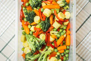 Vegetable mix in plastic storage container on kitchen table.