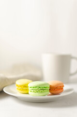 delicious delicate multicolored macaroons on a platter with a cup of coffee in the background with place for text. close-up. selective focus.