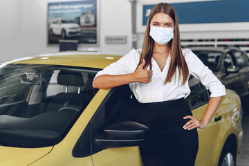 Woman car seller standing near new car wearing protective face mask