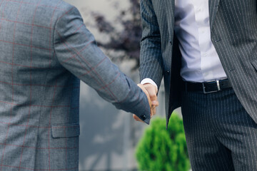 Hands of Top managers in Business Suits, shake hands with each other at Business center background. Agree to a deal or say hello. Unrecognizable person.