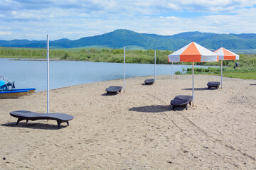 Fototapeta na wymiar Beach lounger with umbrella for sun protection.