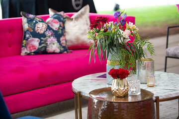 Flowers setup on a coffee table with a pink couch in the back ground.