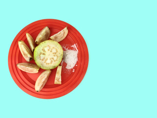 Top view of Guava fruit cut slices served in plate with salt on cyan background with Space for text