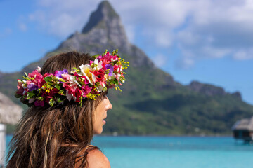 Beautiful woman wearing colorful flower crown while on a tropical island vacation in Bora Bora near Tahiti in French Polynesia - obrazy, fototapety, plakaty