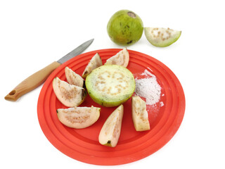 Guava fruit cut slices served in plate with salt on White background with Space for text