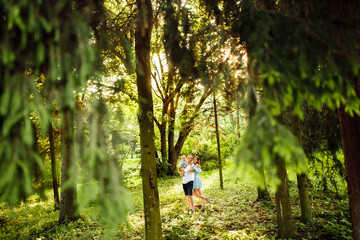 Lovely couple with little daughter walking at the park, caring father hold in arms cute toddler, attractive woman and handsome man hugging, smiling, family moments concept