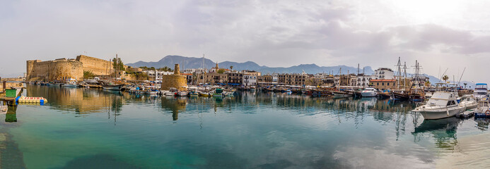 Naklejka premium Panorama across Kyrenia town and harbour in Cyprus from the sea wall of the harbour in springtime