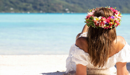 Beautiful woman wearing colorful flower crown while on a tropical island vacation in Bora Bora near...