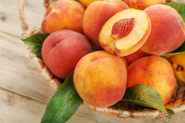 Peaches in a basket on a wooden background with a slice of sliced juicy peach with a stone.