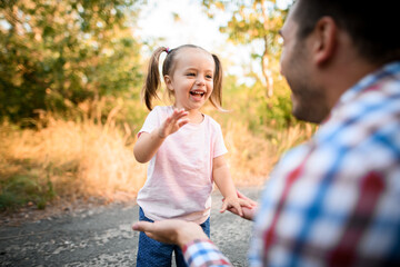 Cheerful little girl plays with her father in the park