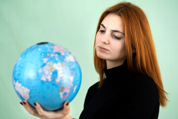Portrait of a sad worried young woman holding geographic globe of the world in her hands. Travel destination and planet protection concept.
