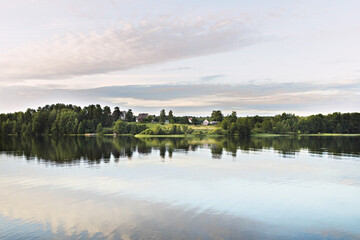 Obraz premium Village by the lake. Reflection of the sky and houses in the water. Sunset