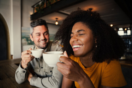 Handsome male joking with beautiful woman over a cup of warm coffee at a chic cafe