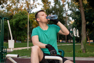 Refreshment during a training in outdoor gym on exercise equipment