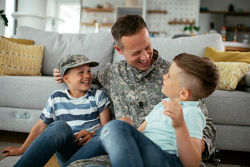 Happy soldier sitting on the floor with his family. Soldier enjoying at home with children..