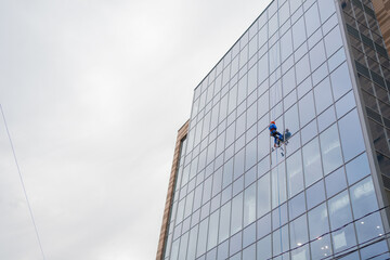 working climber on the glass facade of the building