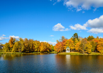 Autumn landscape with a pond in the foreground against blue sky