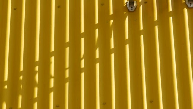 CCTV cameras on facade of industrial building on hot summer day. Building cladding with corrugated steel sheets. Shadows from cameras on yellow wall. Security system of  warehouse or shopping center.