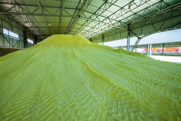 Big yellow sulfur heap at sulfuric acid factory warehouse