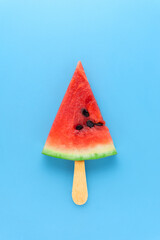 Creative food health diet concept photo of sliced watermelon fruit on stick as ice cream popsicle on blue background.