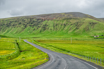Vik, Iceland mountains lush green landscape point of view on ring road trip with cloudy stormy sky and nobody empty highway