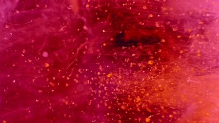 Abstract particles of pink and orange liquid flow and float motion on black - Powered by Adobe