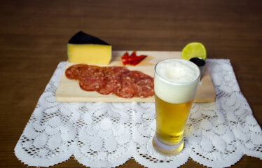 cold cuts board with parmesan cheese, salami with a touch of red pepper and lemon accompanied by beer and cachaça