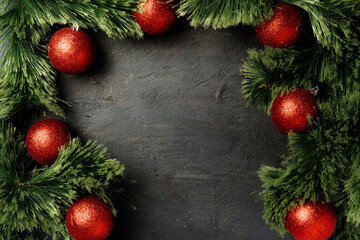 Christmas background with fir tree branches and red baubles on black