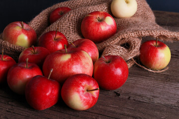 Red apples with burlap sackcloth rough wooden table. Closeup view. Natural organic food, agriculture, horticulture, harvest season concept