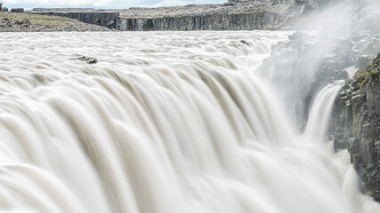 Icelandic Dettifoss waterfall panorama view in Iceland gray long exposure smooth water in motion and rocky cliff spraying