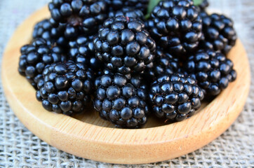 Freshly picked ripe blackberries on a wooden plate on the table.Healthy eating,vegan food or diet concept.Selective focus.